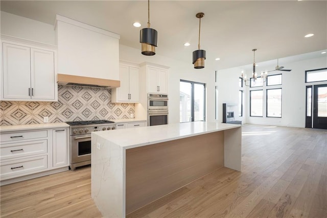 kitchen featuring white cabinetry, decorative light fixtures, a center island, and appliances with stainless steel finishes