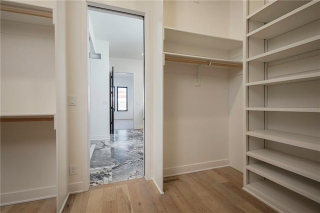 walk in closet with light hardwood / wood-style flooring