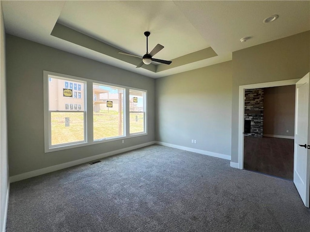 17178 S Heatherwood St, Olathe, KS 66062 - carpeted empty room featuring a ceiling fan, a raised ceiling, and a fireplace