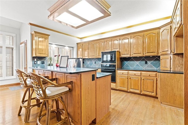 kitchen with black appliances, backsplash, a kitchen bar, kitchen peninsula, and light wood-type flooring