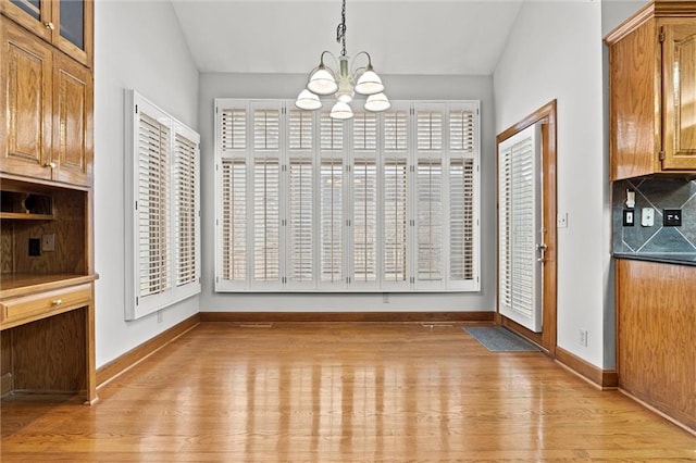 unfurnished dining area featuring a chandelier and light hardwood / wood-style flooring