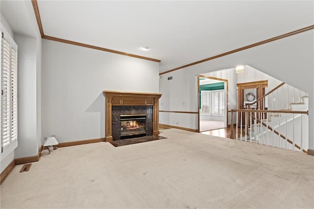 unfurnished living room featuring carpet floors, a wealth of natural light, a high end fireplace, and crown molding