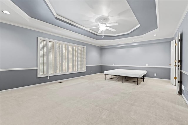 rec room featuring crown molding, a tray ceiling, light colored carpet, and ceiling fan