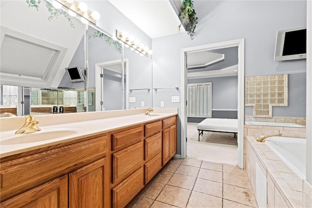 bathroom with vanity, a tray ceiling, tile patterned flooring, and tiled tub