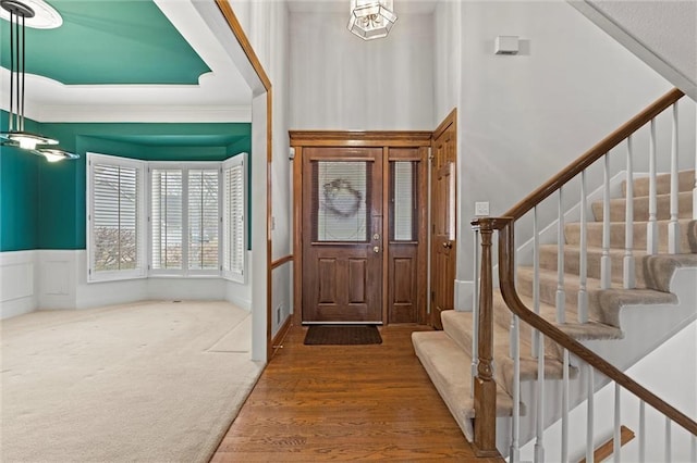 carpeted foyer entrance featuring ornamental molding