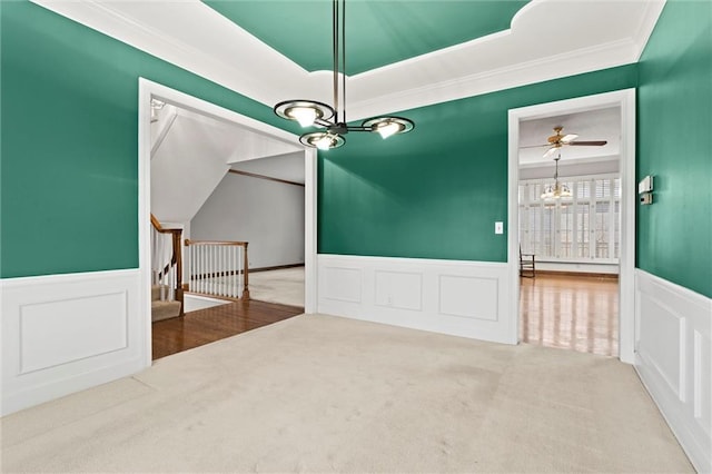 unfurnished room with ornamental molding, ceiling fan with notable chandelier, and carpet