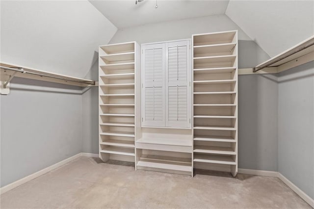 walk in closet featuring lofted ceiling and light colored carpet