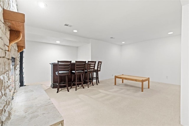 bar featuring a stone fireplace and light carpet