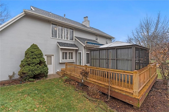 back of property featuring a yard, a sunroom, and a deck