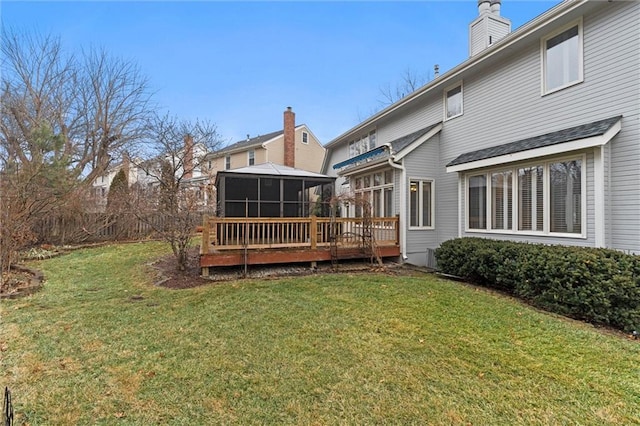 back of property with a sunroom, a deck, and a lawn