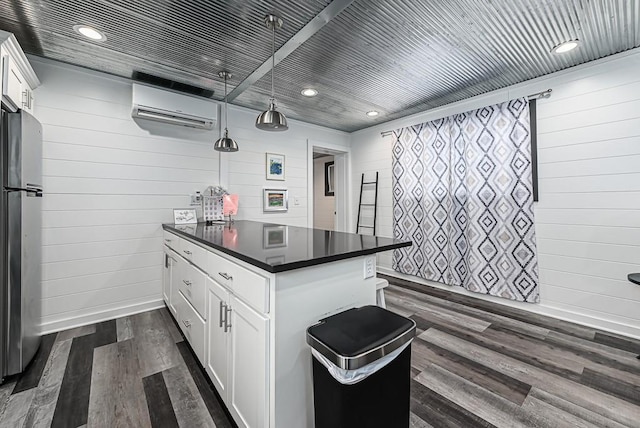 kitchen featuring dark hardwood / wood-style floors, stainless steel refrigerator, white cabinetry, hanging light fixtures, and a wall unit AC