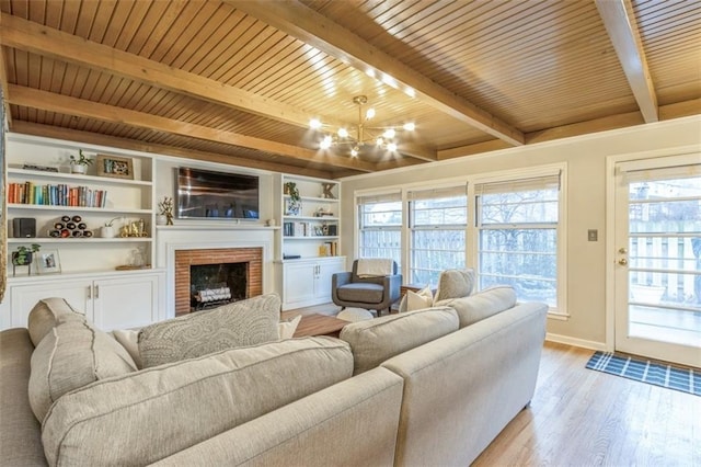 living room with wood ceiling, beam ceiling, a notable chandelier, light hardwood / wood-style floors, and a brick fireplace