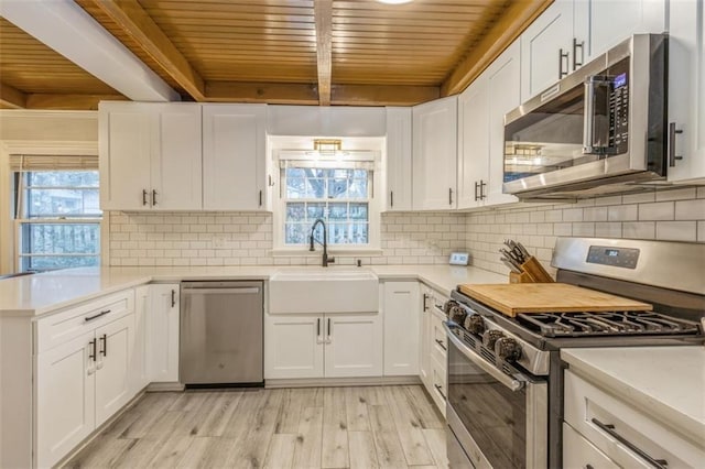 kitchen featuring white cabinetry, appliances with stainless steel finishes, sink, and beam ceiling