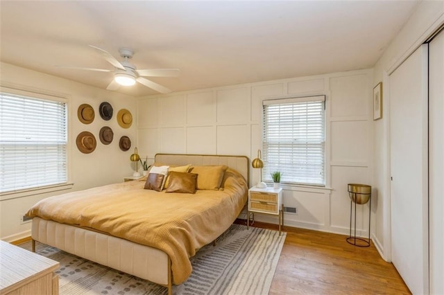 bedroom with ceiling fan, hardwood / wood-style floors, and multiple windows