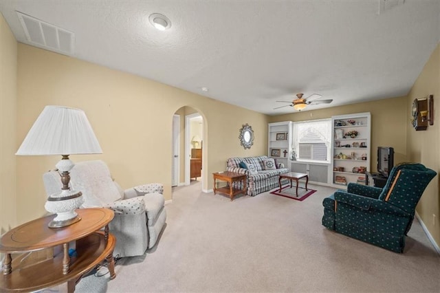 living room with arched walkways, a textured ceiling, visible vents, baseboards, and carpet