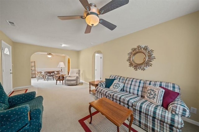 living area featuring carpet floors, visible vents, arched walkways, and baseboards