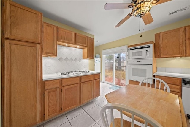 kitchen featuring light tile patterned floors, white appliances, visible vents, light countertops, and decorative backsplash