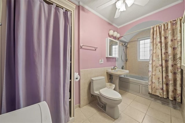 bathroom with toilet, tile patterned flooring, shower / bath combo with shower curtain, crown molding, and tile walls