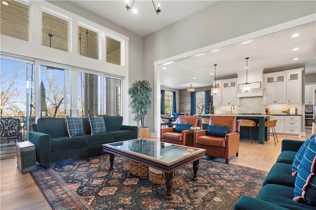 living room with recessed lighting, a notable chandelier, and light wood-style flooring