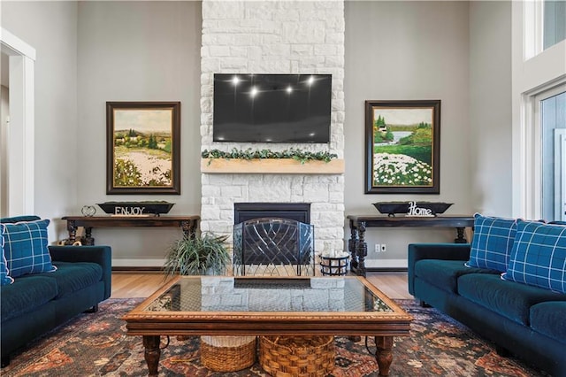 living area with a fireplace, wood finished floors, and baseboards