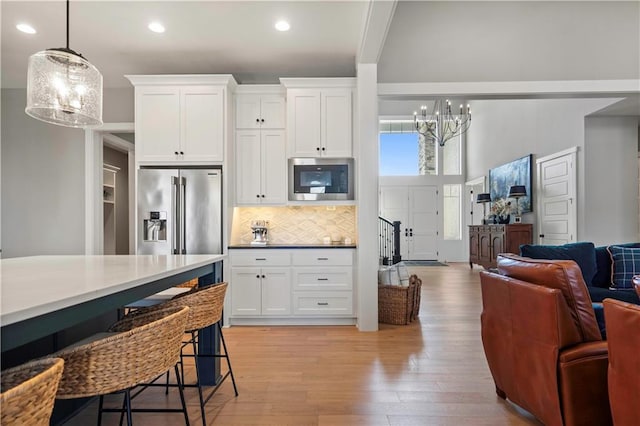 kitchen featuring high end refrigerator, hanging light fixtures, built in microwave, light countertops, and a notable chandelier