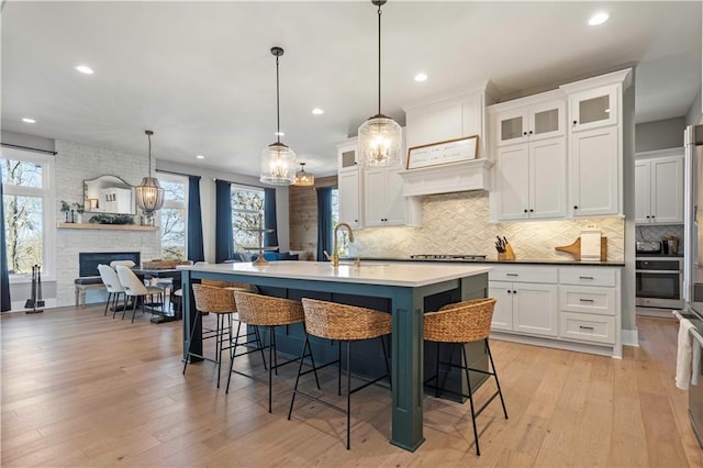 kitchen with pendant lighting, light countertops, open floor plan, and a kitchen island with sink