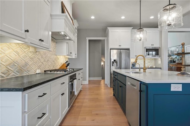 kitchen with dark countertops, appliances with stainless steel finishes, white cabinetry, and decorative light fixtures