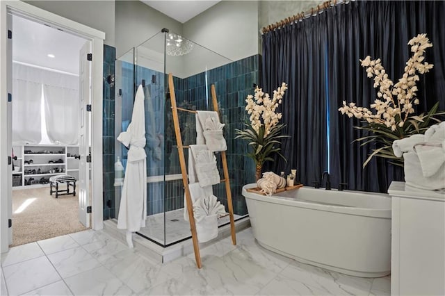 bathroom featuring a stall shower, marble finish floor, and a soaking tub