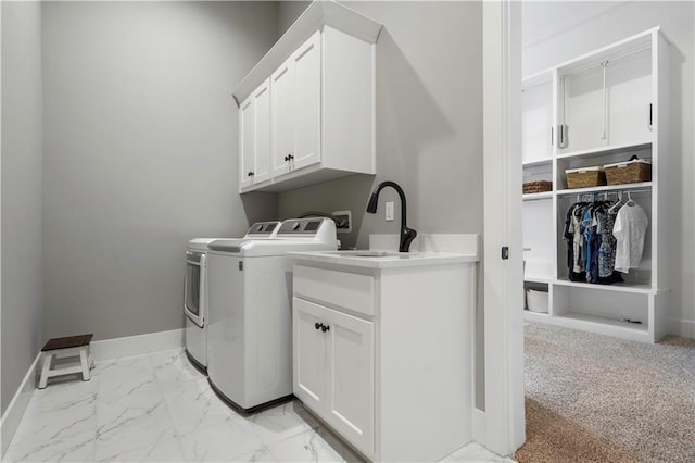 laundry room with cabinet space, baseboards, washing machine and clothes dryer, marble finish floor, and a sink