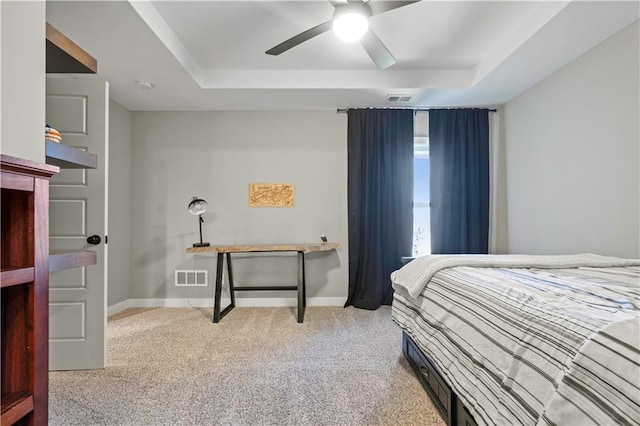 bedroom with a raised ceiling, visible vents, and light colored carpet