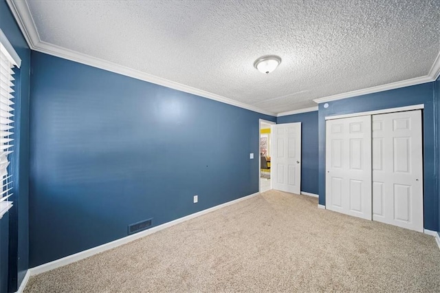 unfurnished bedroom with crown molding, a closet, a textured ceiling, and carpet flooring