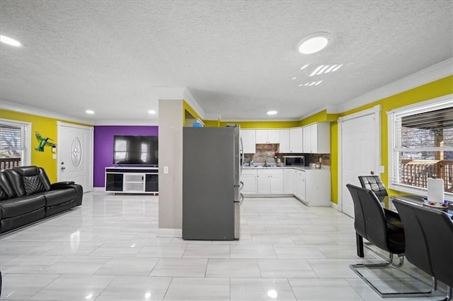 kitchen with white cabinetry, appliances with stainless steel finishes, a textured ceiling, and backsplash