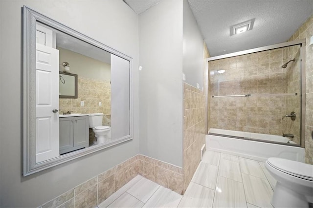 full bathroom featuring bath / shower combo with glass door, vanity, a textured ceiling, tile patterned floors, and toilet