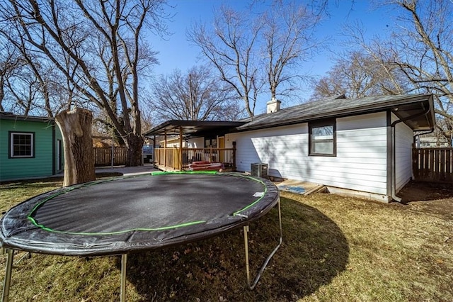 view of yard featuring cooling unit, a deck, and a trampoline