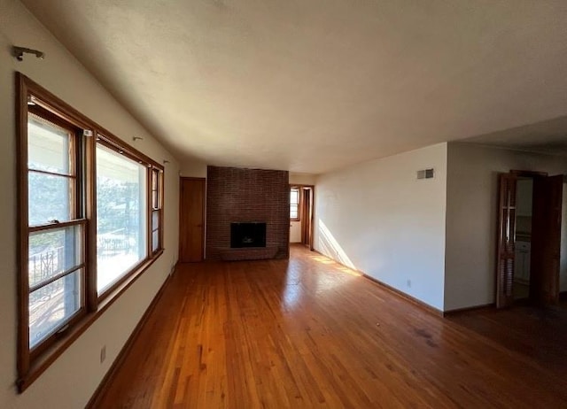 unfurnished living room with a brick fireplace and hardwood / wood-style flooring