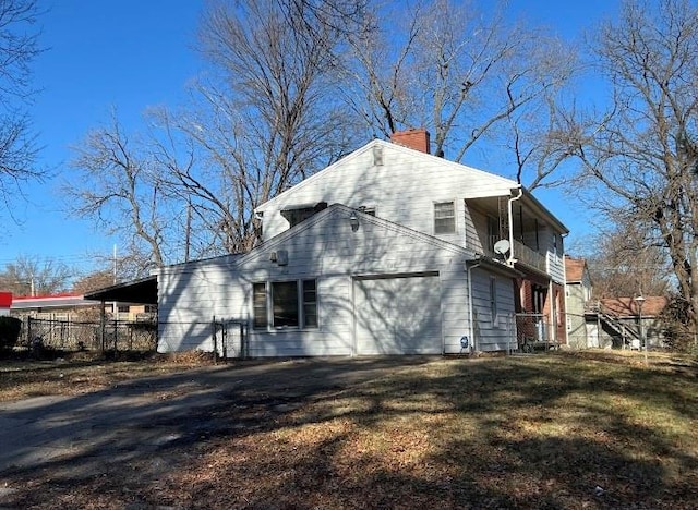 view of side of home featuring a garage, a balcony, and a yard