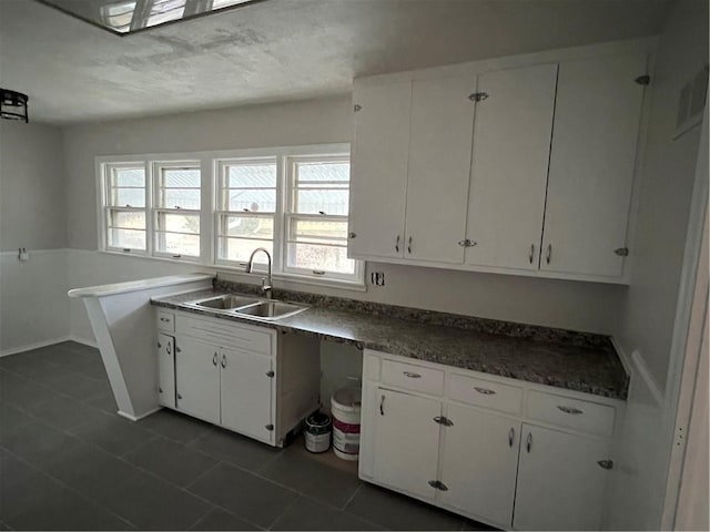 kitchen featuring white cabinetry, dark tile patterned flooring, and sink