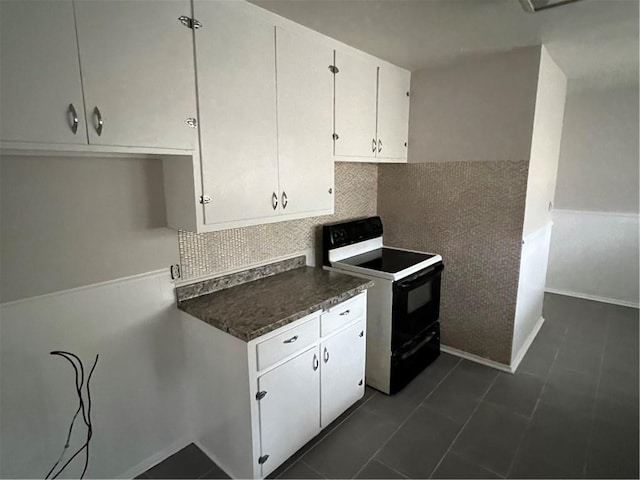 kitchen with white cabinetry, dark tile patterned flooring, decorative backsplash, and electric range