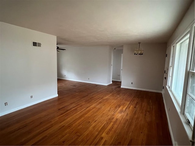 unfurnished room featuring dark wood-type flooring and ceiling fan with notable chandelier