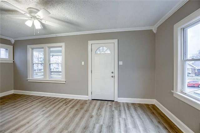 foyer entrance featuring light hardwood / wood-style flooring, ornamental molding, and a textured ceiling