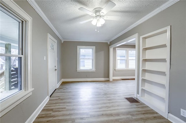 empty room with ceiling fan, ornamental molding, light hardwood / wood-style floors, and a textured ceiling