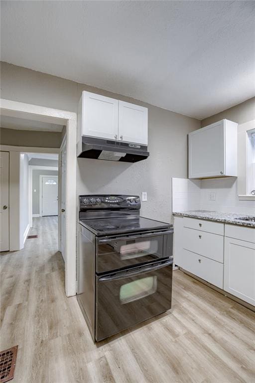 kitchen with sink, white cabinetry, light wood-type flooring, double oven range, and light stone countertops