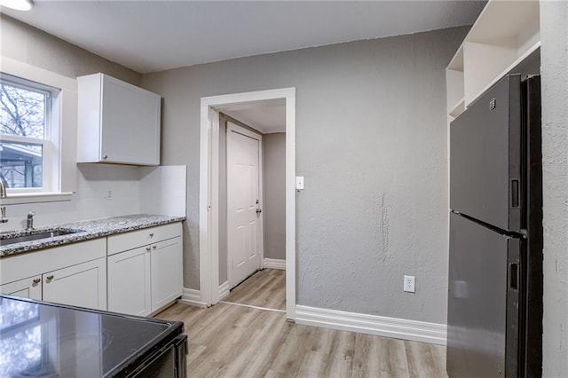 kitchen featuring white cabinetry, sink, light hardwood / wood-style flooring, and black appliances