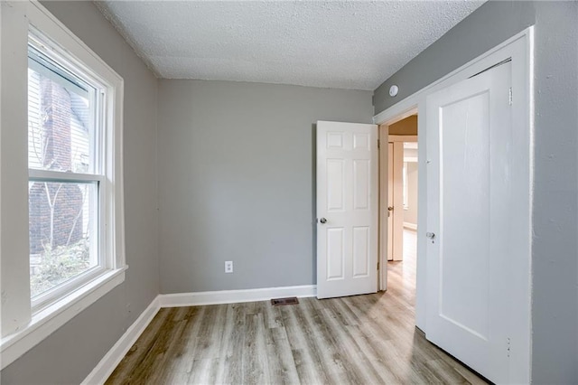 unfurnished room with a textured ceiling and light hardwood / wood-style floors