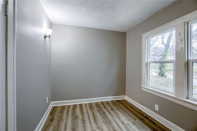 empty room with a textured ceiling and light hardwood / wood-style flooring