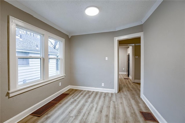 empty room with crown molding, a textured ceiling, and light hardwood / wood-style floors