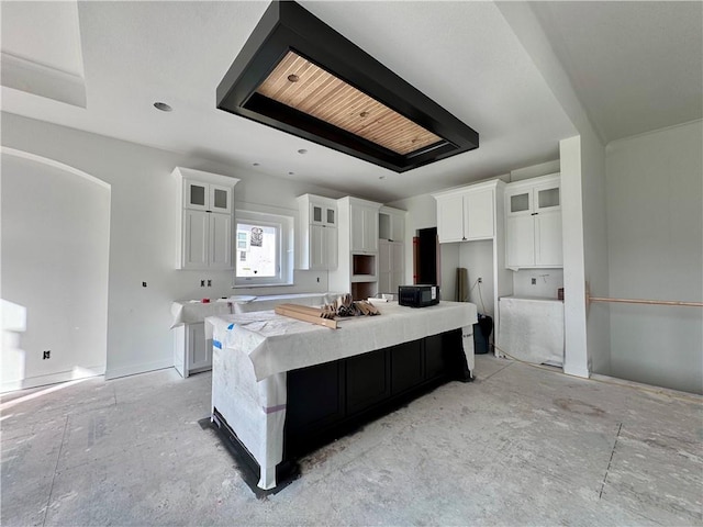 10332 N Potter Ave, Kansas City, MO 64157 - kitchen with white cabinetry, a spacious island, glass insert cabinets, black microwave, and light countertops