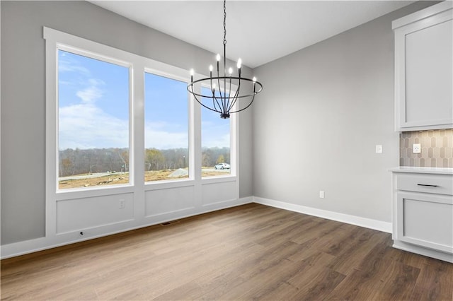 unfurnished dining area featuring an inviting chandelier and light wood-type flooring