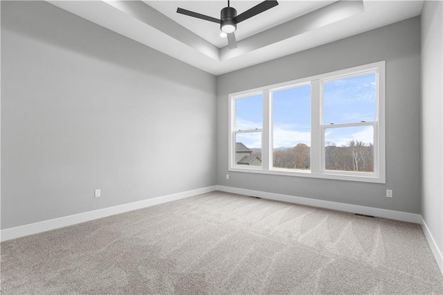 carpeted spare room featuring a raised ceiling and ceiling fan