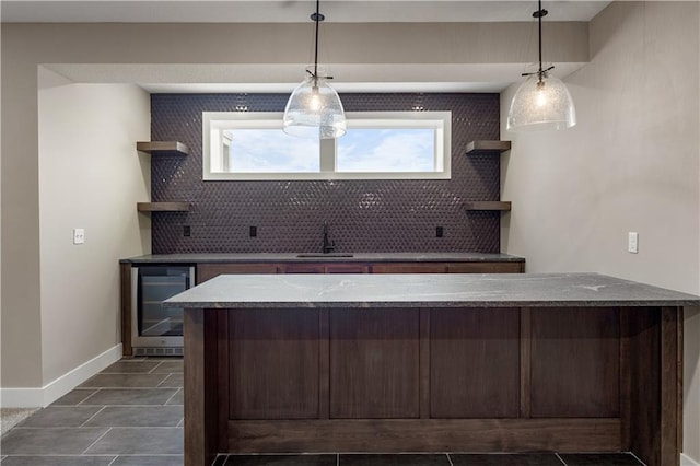 kitchen with pendant lighting, sink, decorative backsplash, and beverage cooler